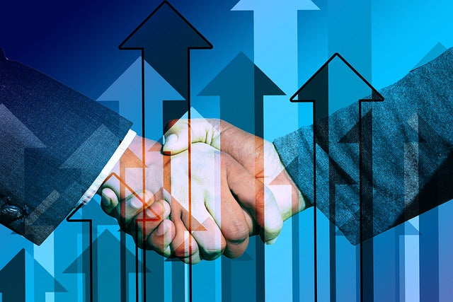 Zwei Personen in Geschäftskleidung schütteln über digitalen blauen und schwarzen Aufwärtspfeilen, die Wachstum symbolisieren, die Hände, während sie mit Akquiseschreiben/Werbebrief eine wirksame Strategie entwickeln, um die Kundenakquise zu verbessern und ihre Bemühungen voranzutreiben.