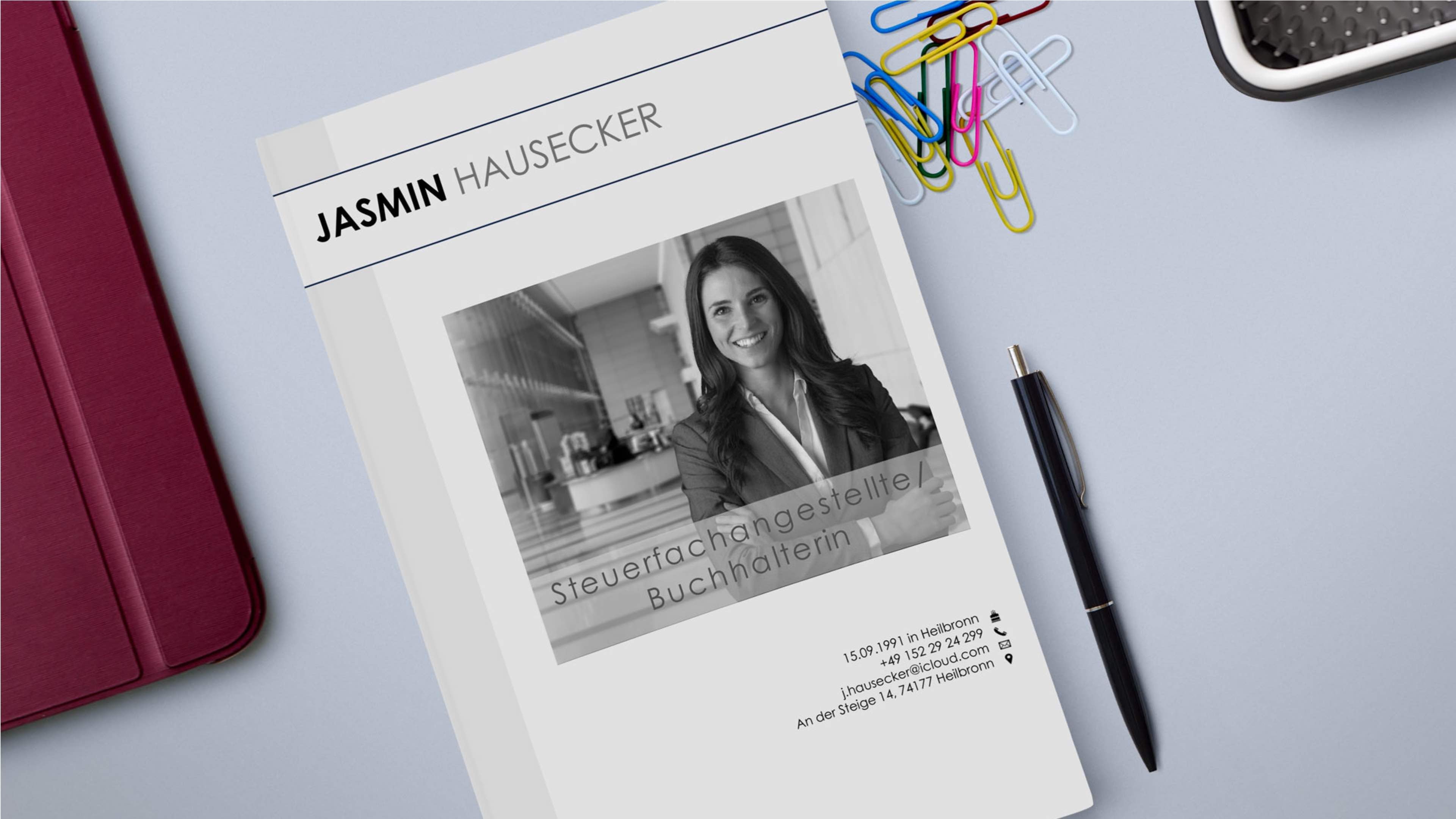 Draufsicht auf einen Schreibtisch mit einer Zeitschrift, auf deren Titelseite das Graustufenfoto einer Geschäftsfrau steht. Ihr Name ist darüber gedruckt. Daneben liegen ein Stift, bunte Büroklammern und ein roter Ordner. Im Text wird sie als Steuerberaterin und Buchhalterin mit Kontaktdaten erwähnt.